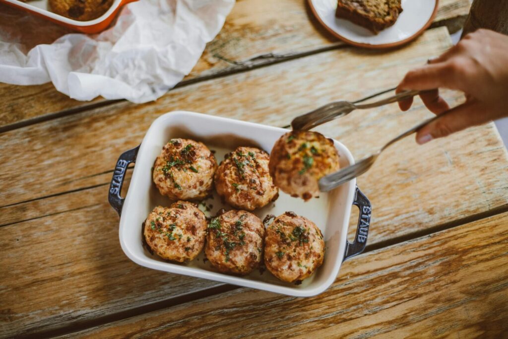 Close-up of homemade meatballs with herbs in a dish on a wooden table. Perfect for food photography.
