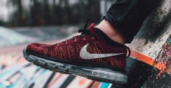 Vibrant red sneaker displayed against a dynamic graffiti wall in outdoor setting.