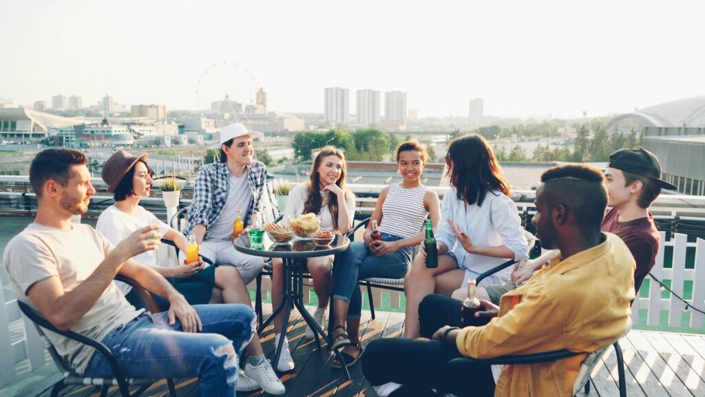 Friends gathered on a rooftop patio with cityscape background.