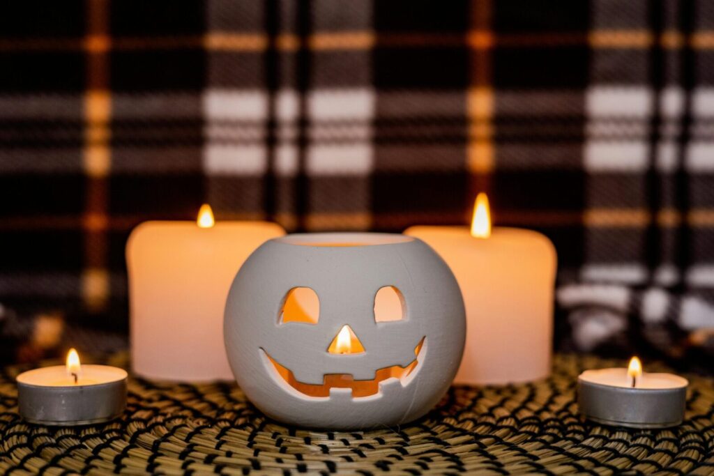 Charming Halloween setup with carved pumpkin surrounded by glowing candles, creating a warm, festive atmosphere.
