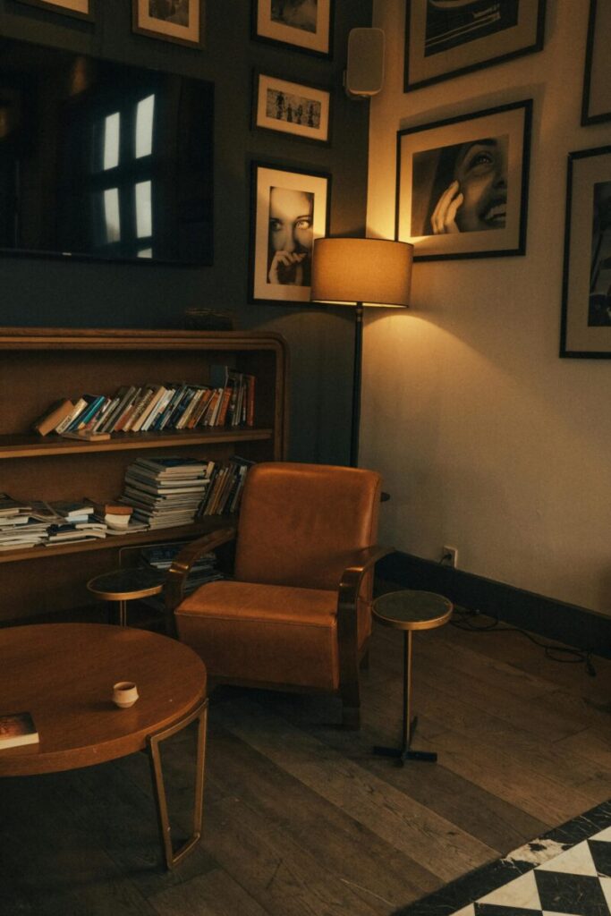 Warm interior with a leather armchair, bookshelf, and lamp in a cozy reading corner.