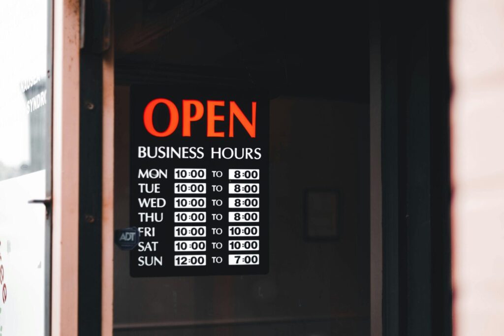 Close-up of an open business hours sign displayed in a shop window.
