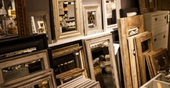 A collection of vintage-style mirror frames on display in a cozy interior shop setup.