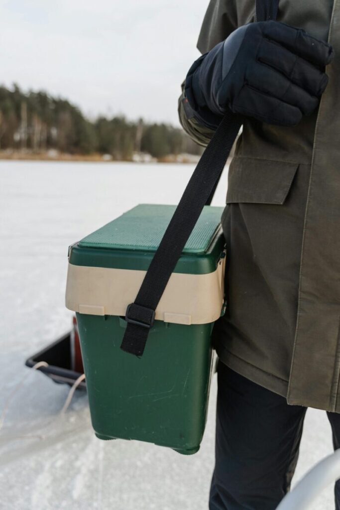 A person carrying ice fishing gear on a frozen lake during winter.