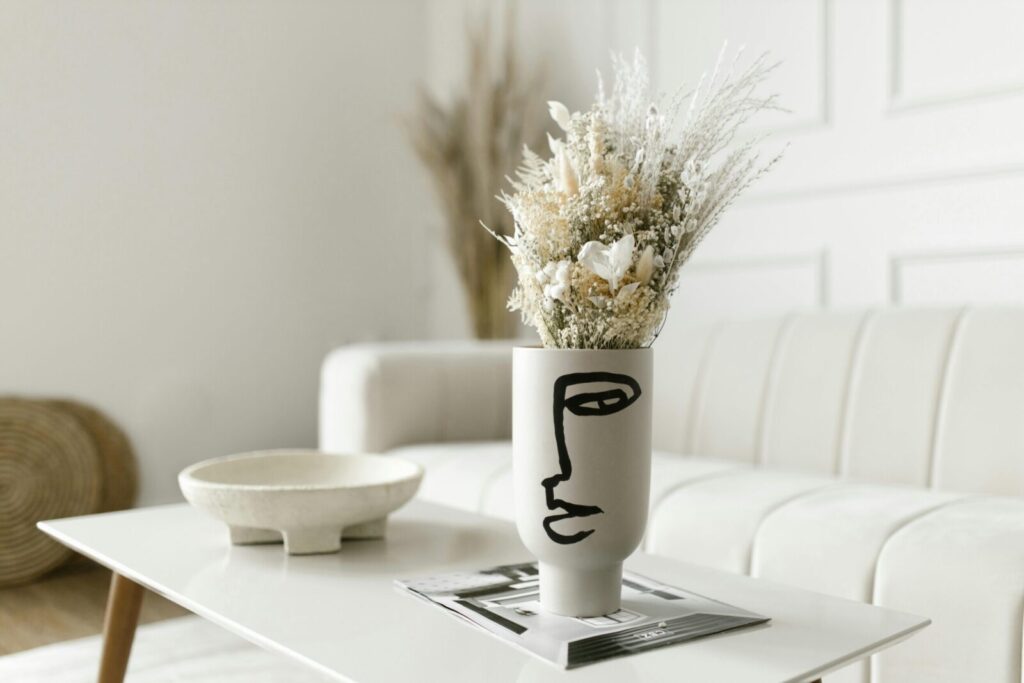 A modern minimalist living room with a white flower bouquet in an artistic face-designed vase.