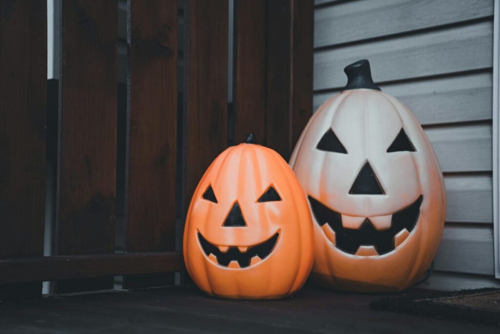 Two jack-o'-lantern pumpkins with carved faces symbolizing Halloween, placed in a home corner.