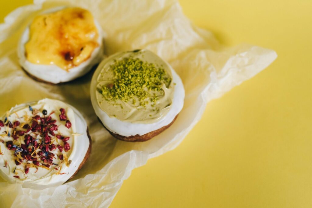 Three gourmet donuts with various toppings on a bright yellow surface, perfect for food photography.