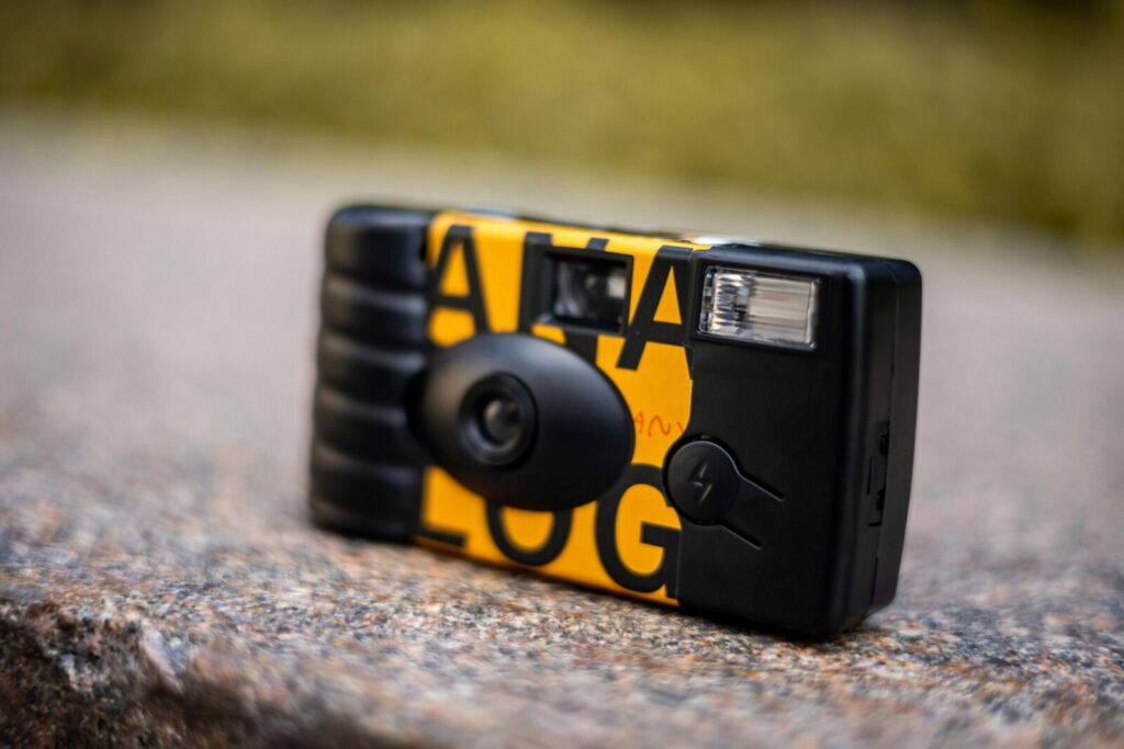 Artistic close-up of a retro disposable camera on a stone surface.