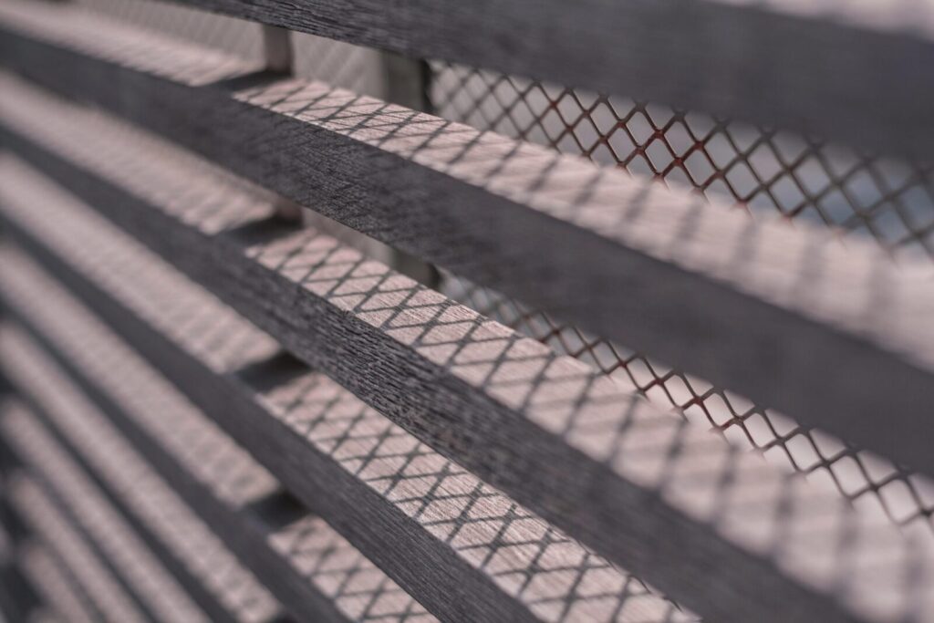 Detailed photo of a slatted wooden fence creating geometric shadow patterns.