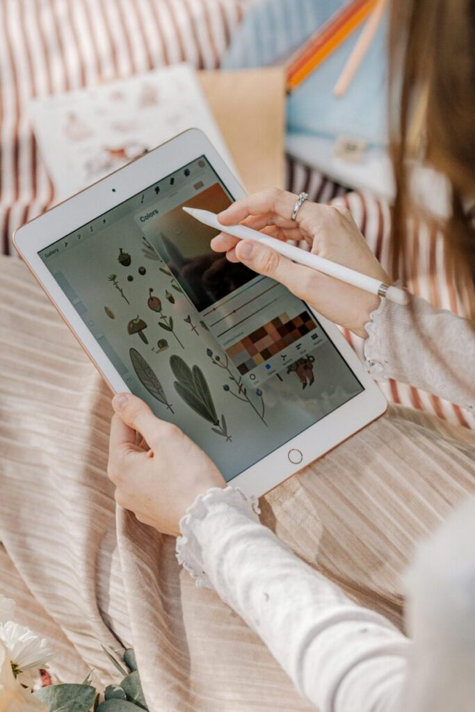 Person drawing digital art on a tablet using a stylus outdoors.