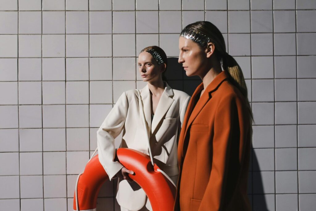 Two women in oversized fashion blazers posing creatively with a lifebuoy.