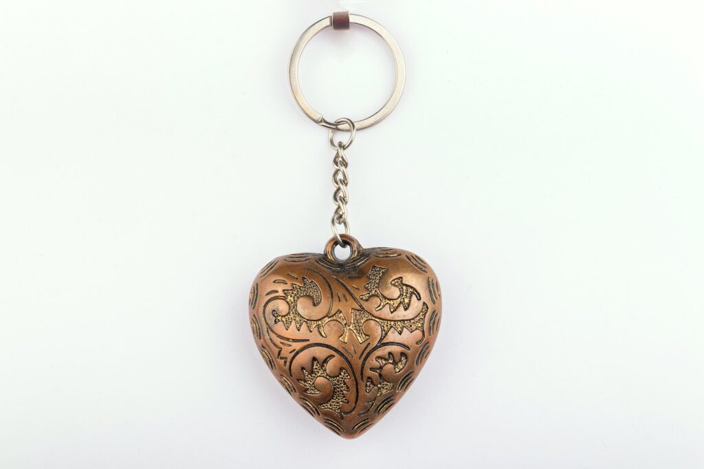 A metal heart shaped keychain hanging from a chain