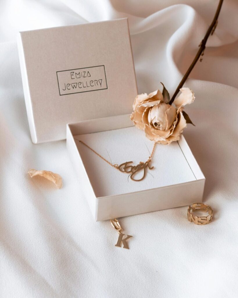 Sophisticated jewelry setup featuring a necklace in a box and a rose on a soft fabric.