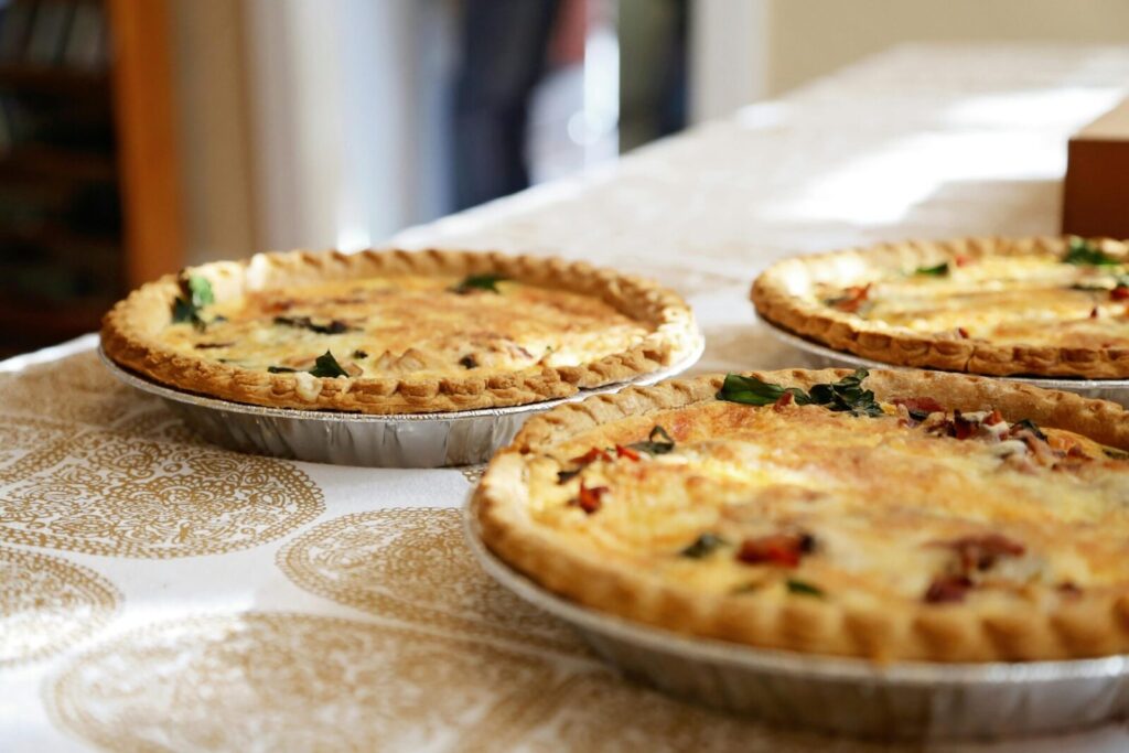 Delightful homemade quiches on a classic patterned tablecloth, inviting and delicious.