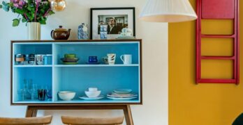 Stylish interior featuring blue shelves with dishes and decor against a colorful backdrop.