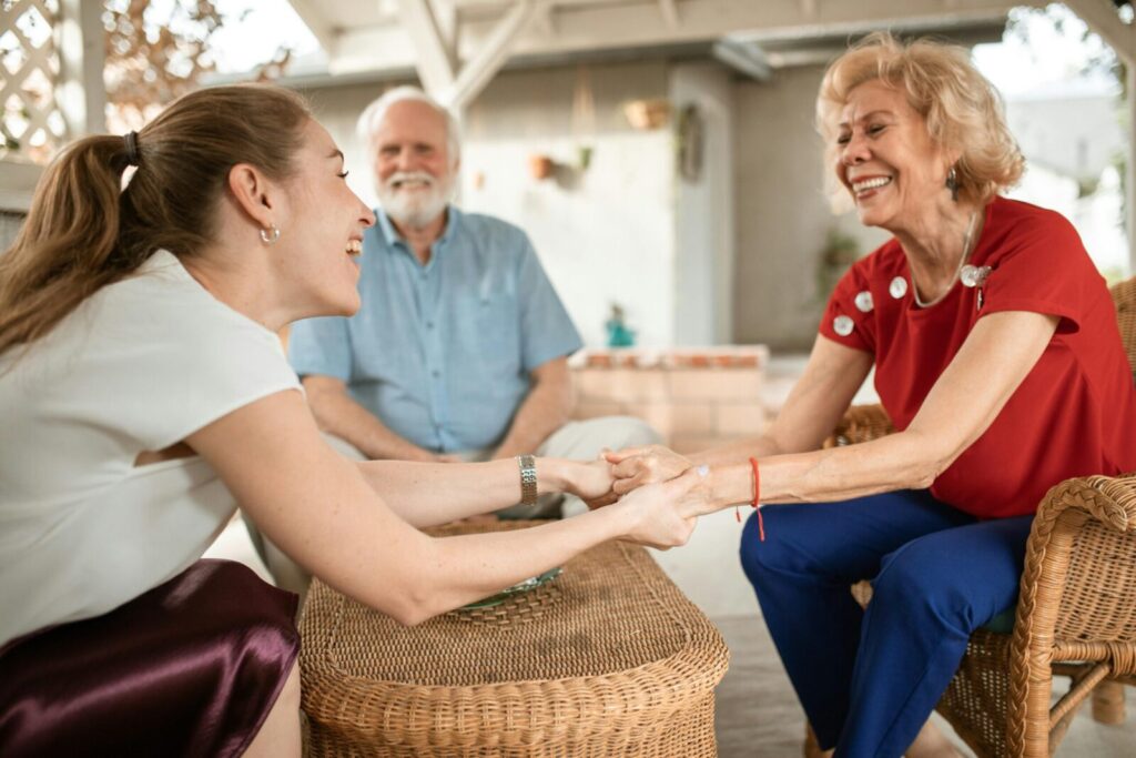 Three family members enjoying a happy conversation outside, sharing laughter and smiles.