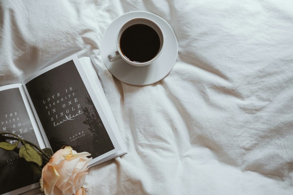 a cup of coffee and a book on a bed