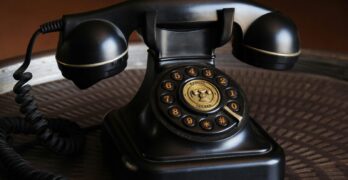 Close-up of a classic black vintage rotary dial telephone on a textured table.