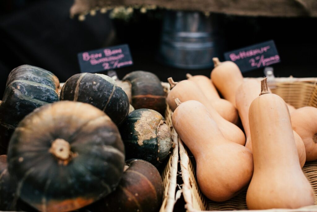 Close-up of fresh butternut and buttercup squashes displayed in baskets at a market.