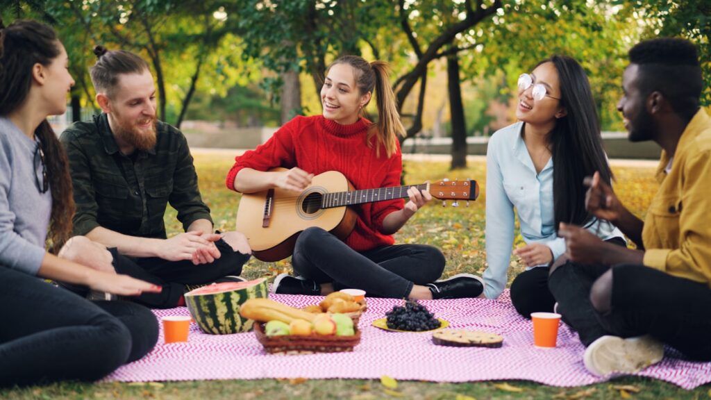 Friends enjoying a picnic and playing guitar
