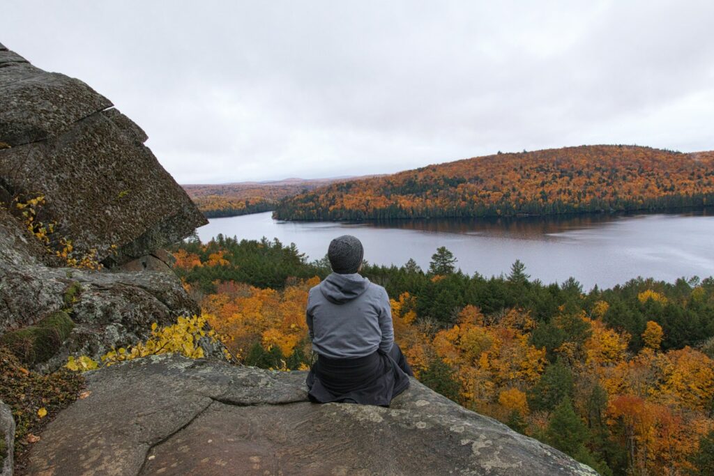 a person sitting on a rock looking at a body of water
