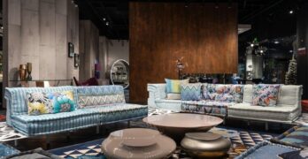 Comfortable sofas with colorful cushions and creative coffee tables placed on carpet in modern spacious furniture store