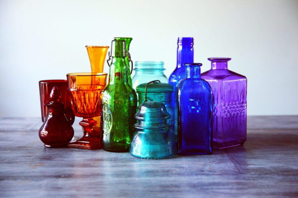 A captivating array of multicolored vintage glass bottles and containers on a wooden table.