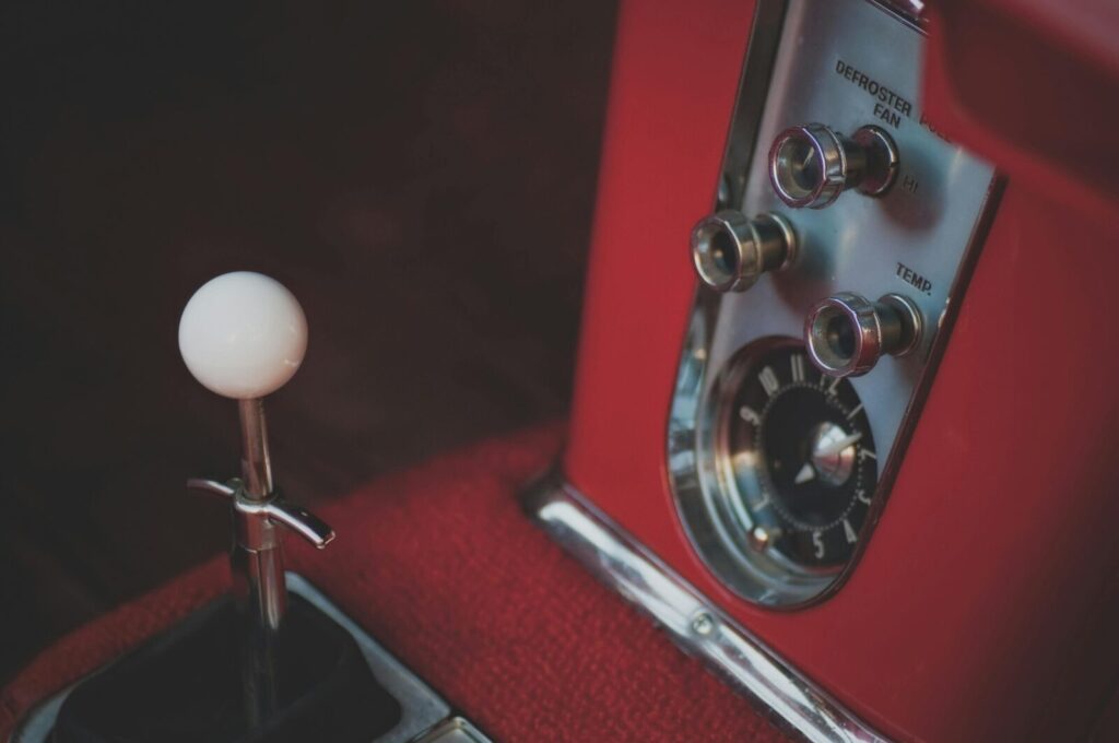 Detailed view of vintage car's stick shift and dashboard controls.