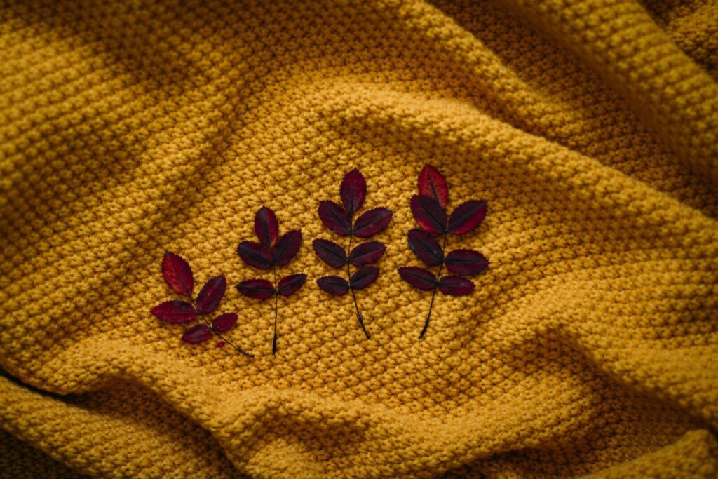 Vibrant autumn leaves displayed on woven yellow textile, showcasing cozy fall aesthetics.