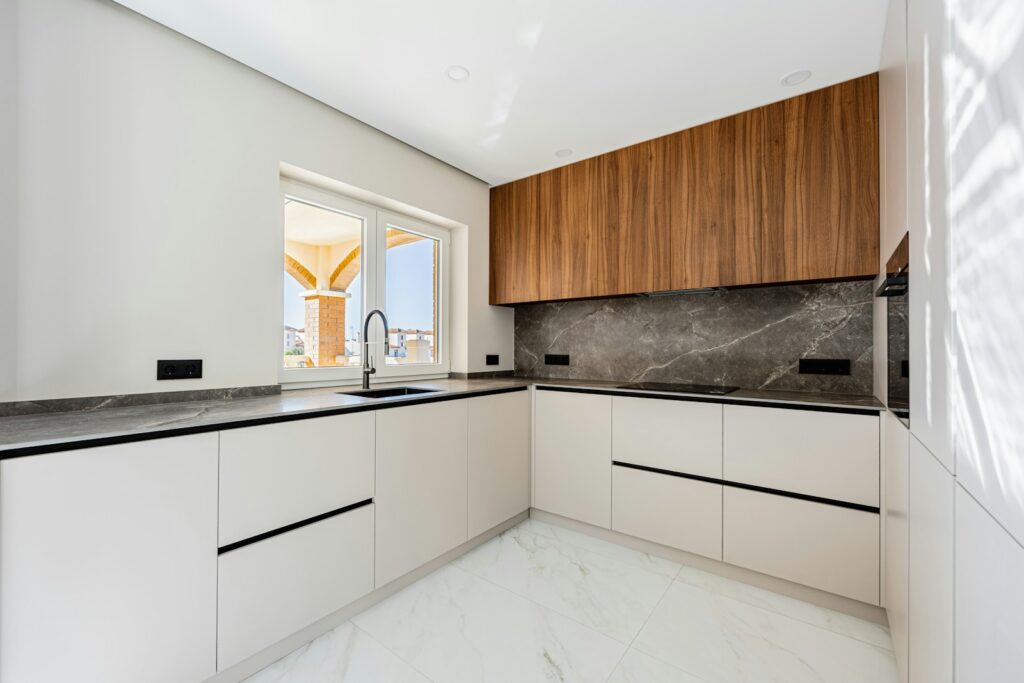 Modern l-shaped kitchen with white cabinets and wood accents.