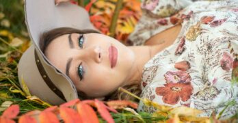 A woman laying in the grass with a hat on her head