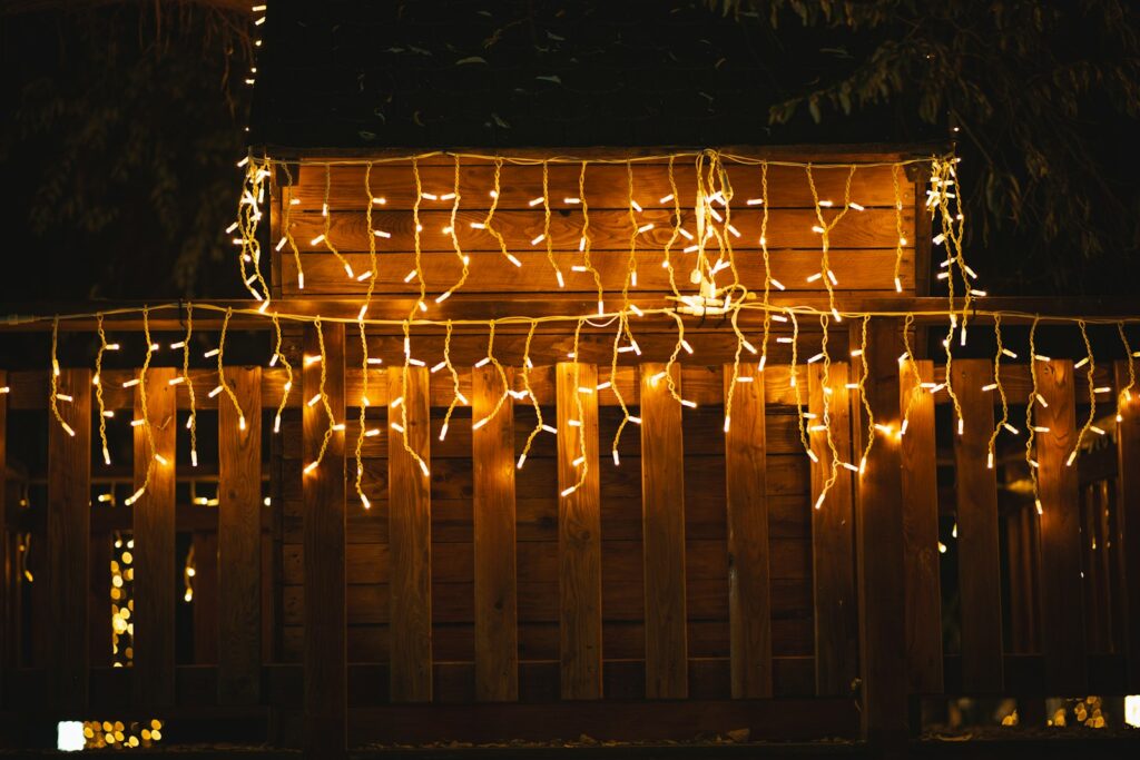 A fence covered in christmas lights at night
