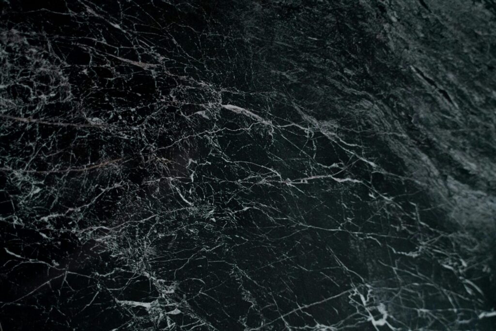 Intricate pattern on a dark marble surface, showcasing natural veins and textures.