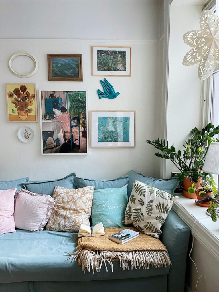 A cozy room with art, plants, cushions, and a window creating a relaxing ambiance.