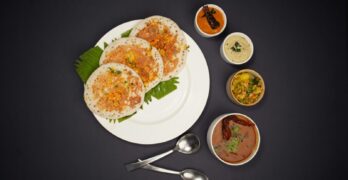 Top view of South Indian dosa served with a variety of chutneys on a black background.