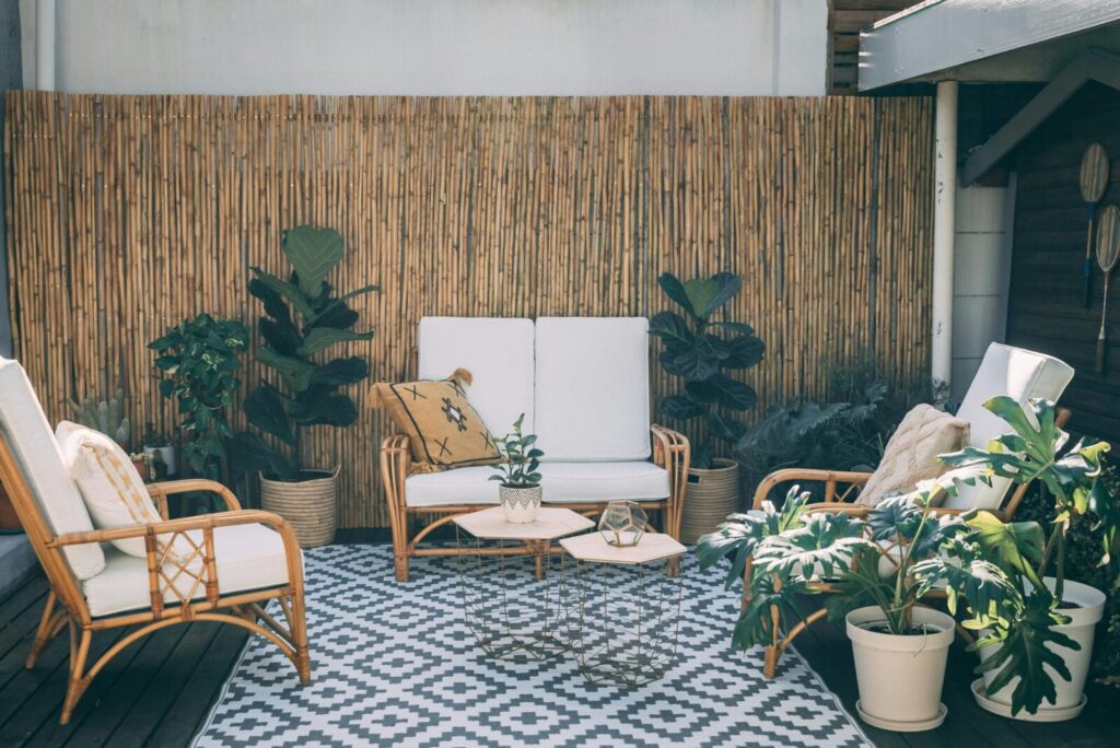 Serene outdoor patio featuring rattan furniture, potted plants, and bamboo decor.