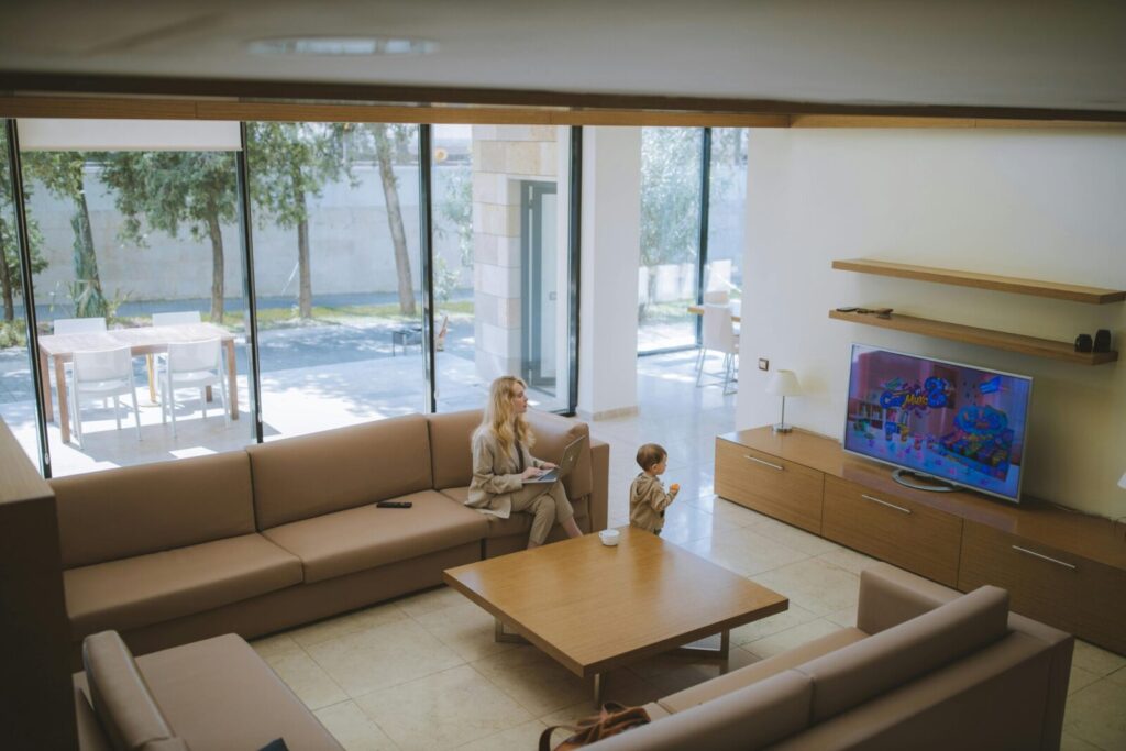 Bright and spacious living room with a woman and child watching TV in a modern home.
