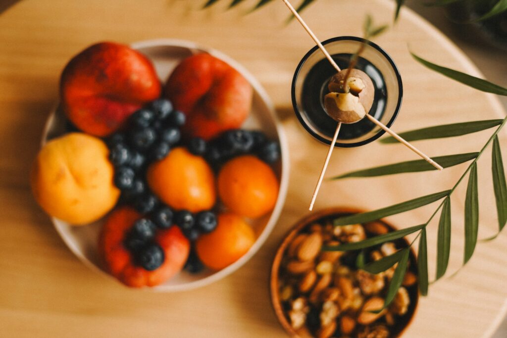 A plate of fruit and a bowl of nuts on a table