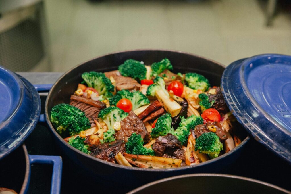 A colorful dish of roasted vegetables and meat in a blue casserole pot, ideal for family dinners.