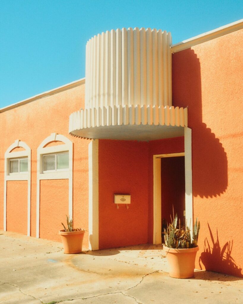 Sunny outdoor view of an orange house with potted plants at Algiers Point, New Orleans.