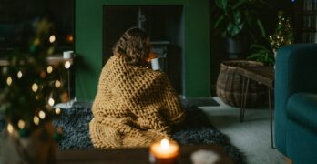a woman wrapped in a blanket sitting on a rug in a living room
