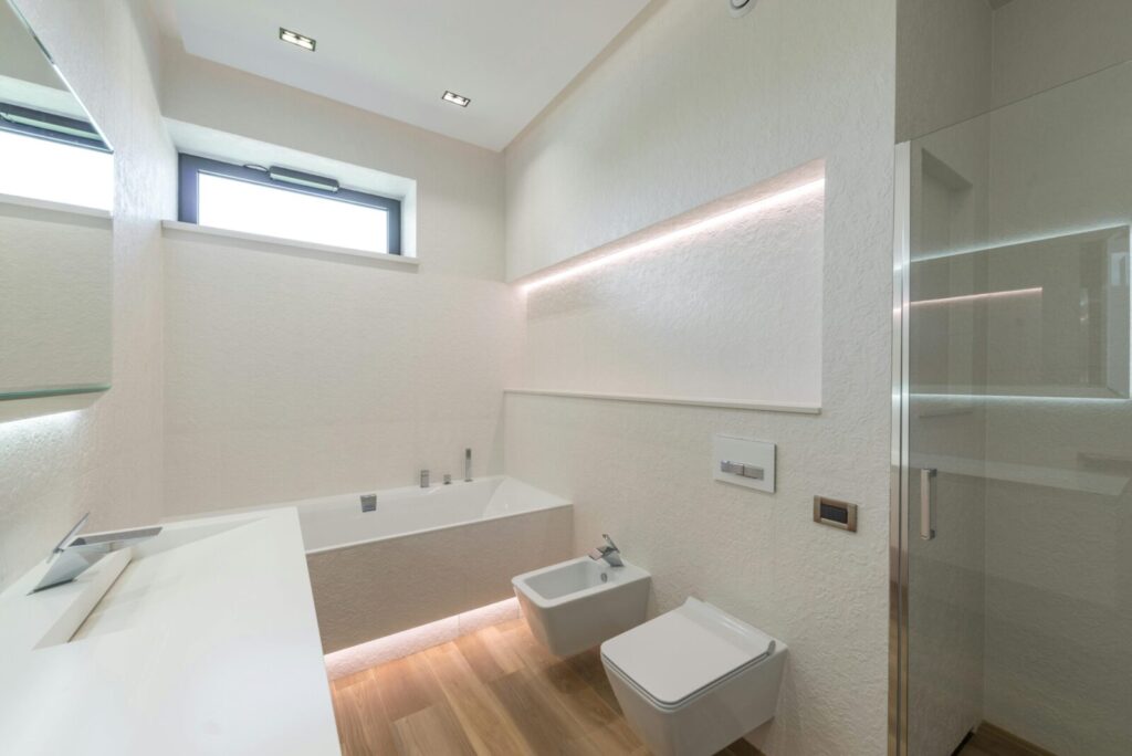 Interior design of modern minimalist luxury style bathroom with white walls and LED illumination equipped with washbasin and toilet and sink and bathtub