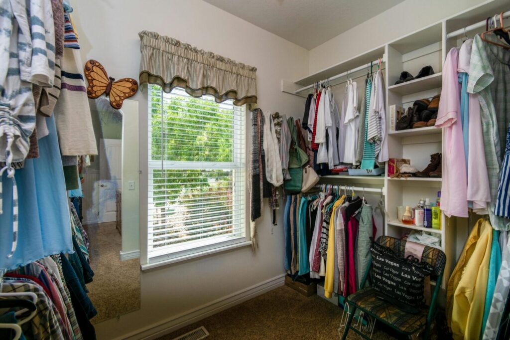 A bright and organized walk-in closet with clothes, shelves, and a window view.