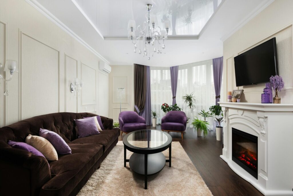 Luxurious living room featuring elegant decor with purple accents, chandelier, and fireplace.