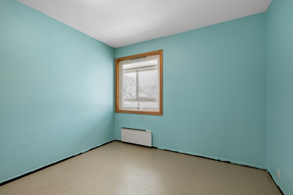 A empty room with a window and a radiator