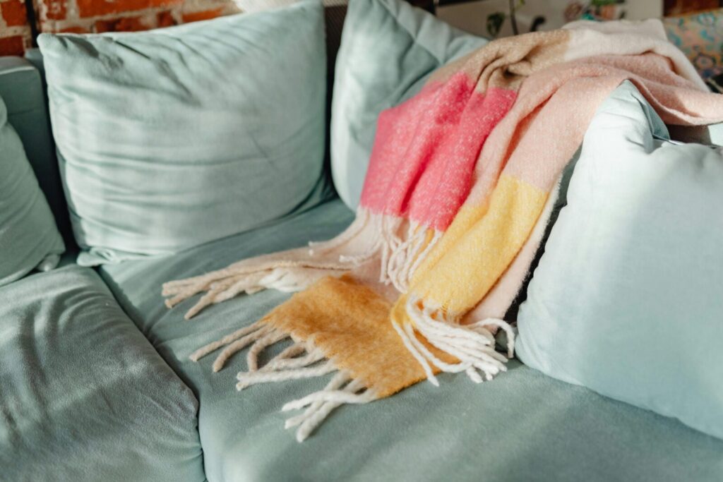 A warm colorful blanket draped on a teal sofa, adding cozy charm to a living room interior.