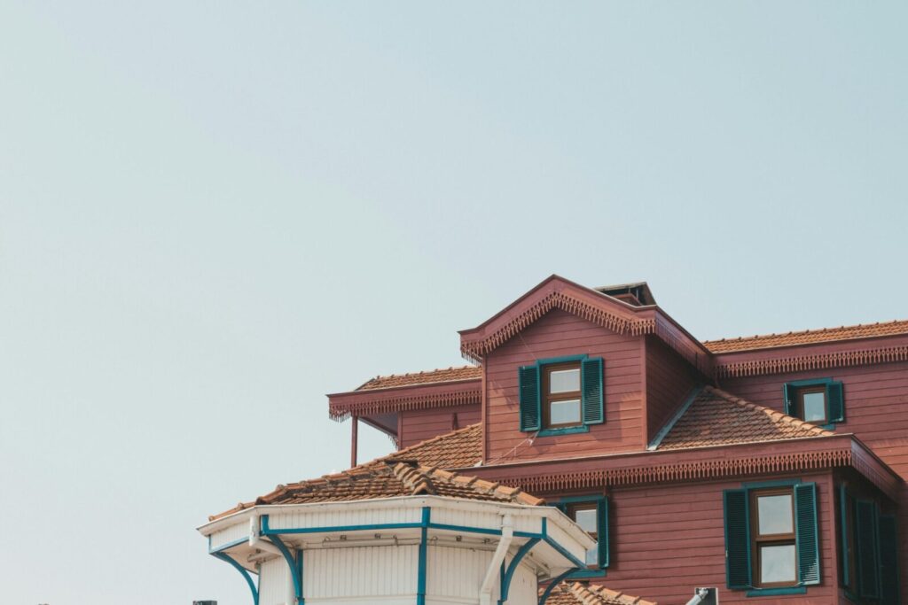 A captivating image of a traditional house featuring a unique roof design with wooden accents and vibrant shutters.