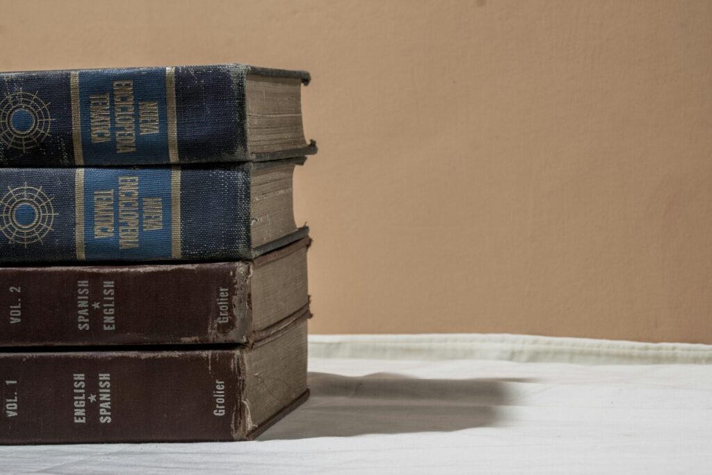 A stack of old encyclopedias and dictionaries with copy space on a neutral background.