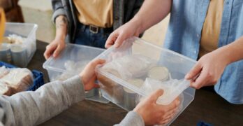 Close-up of volunteers distributing food packages during a charity event.