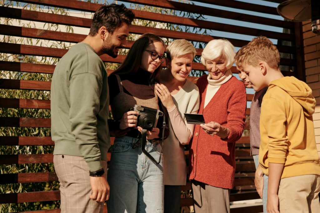 A family of various ages sharing a joyful moment outdoors with a vintage camera.
